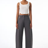 Woman wearing a white tank top and gray pants on a white background