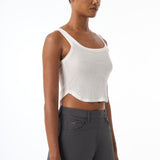 Woman wearing a white tank top and gray pants on a white background