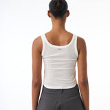 Woman wearing a white tank top and gray pants on a white background