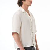 Man wearing a white button-up shirt with rolled-up sleeves on a white background