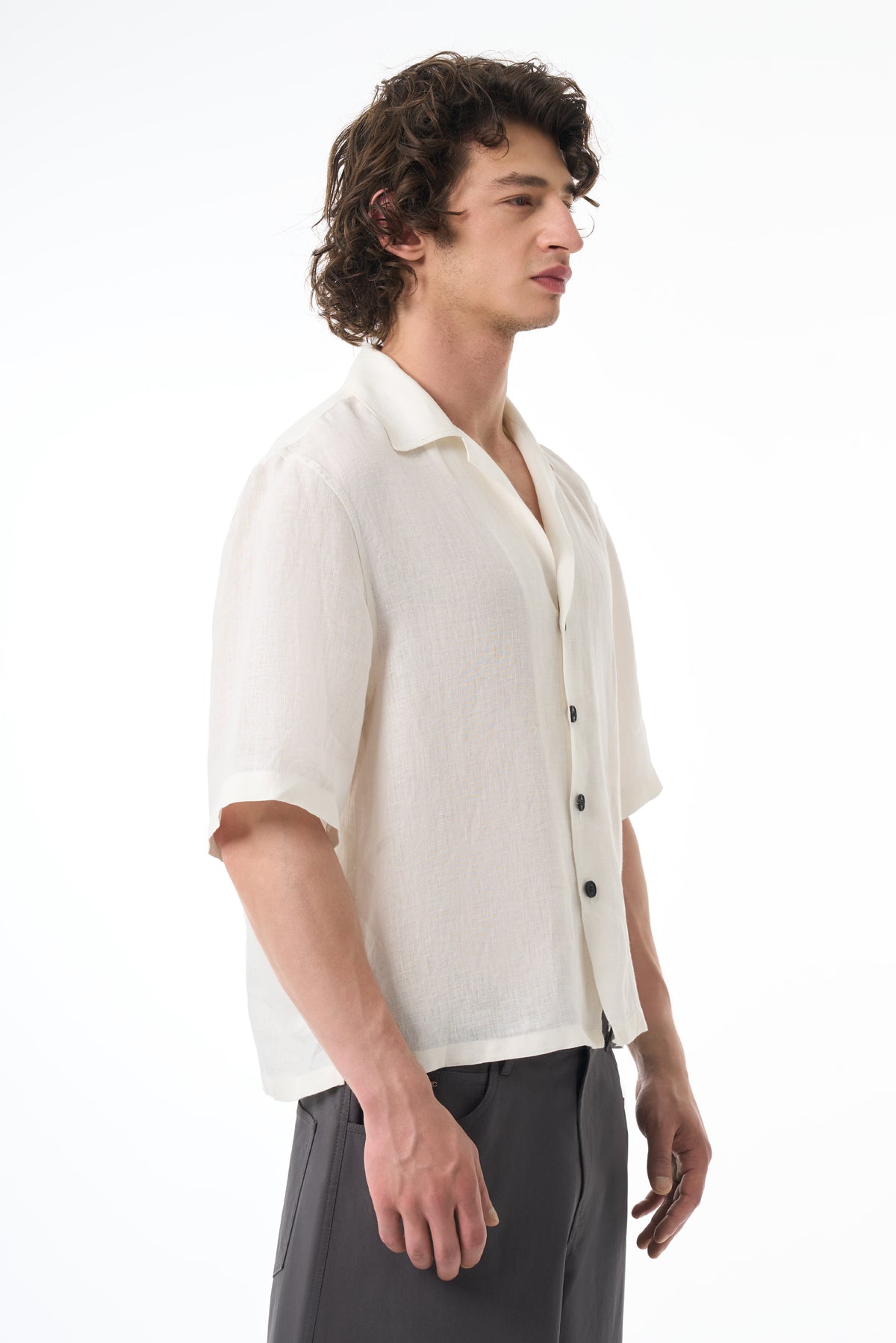 Man wearing a white button-up shirt with rolled-up sleeves on a white background