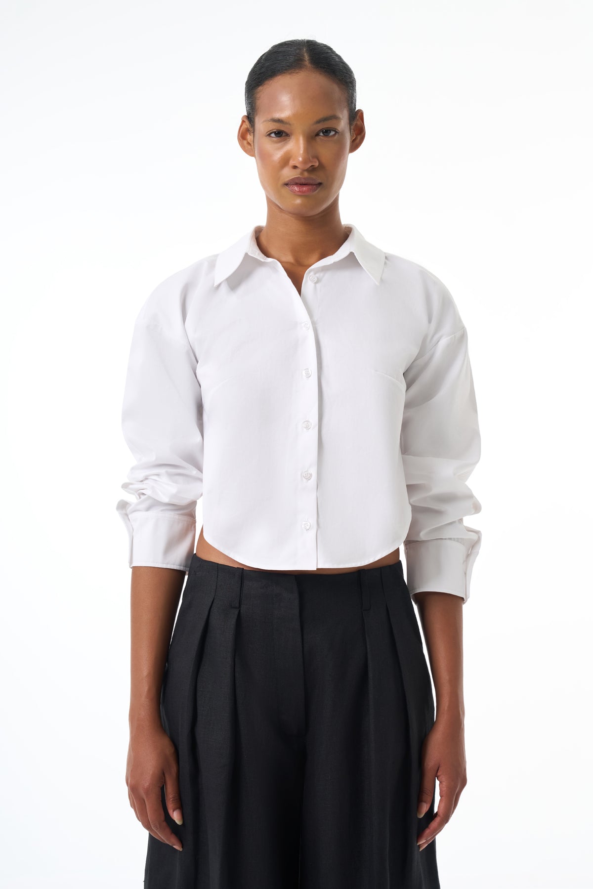 Woman wearing a white button-up shirt and black pants on a white background