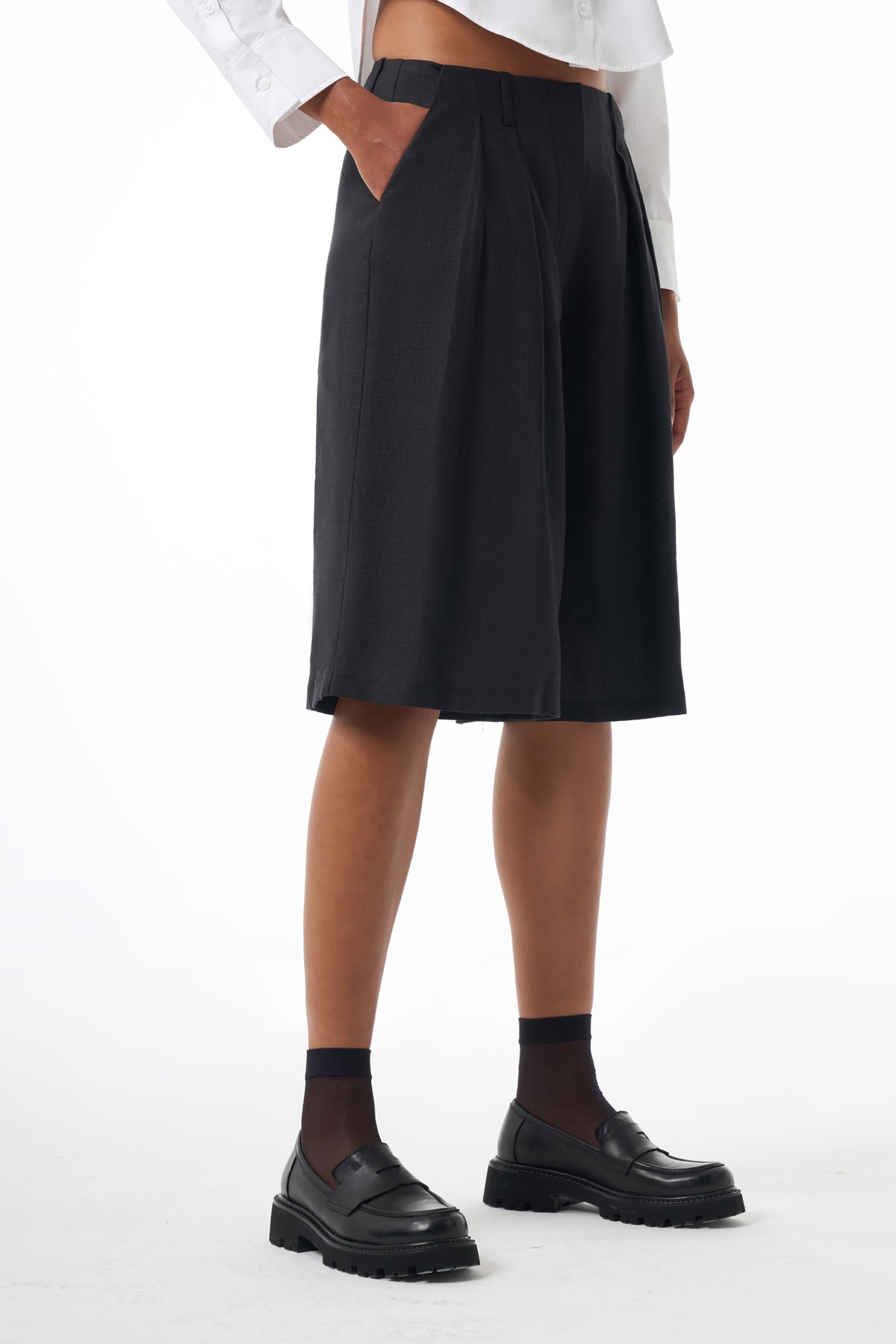 Woman wearing a black skirt, white shirt, and black shoes on a white background