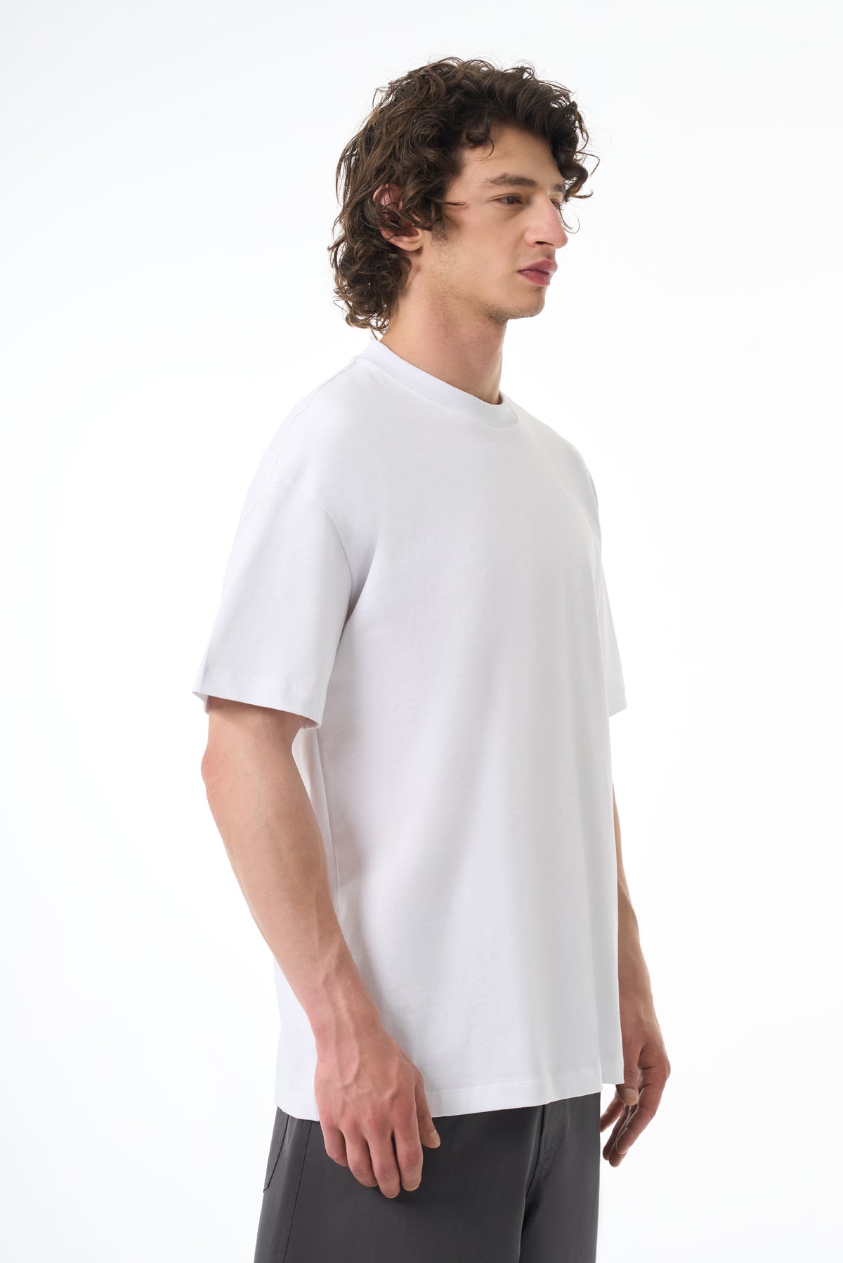 Man wearing a white t-shirt and gray pants on a white background
