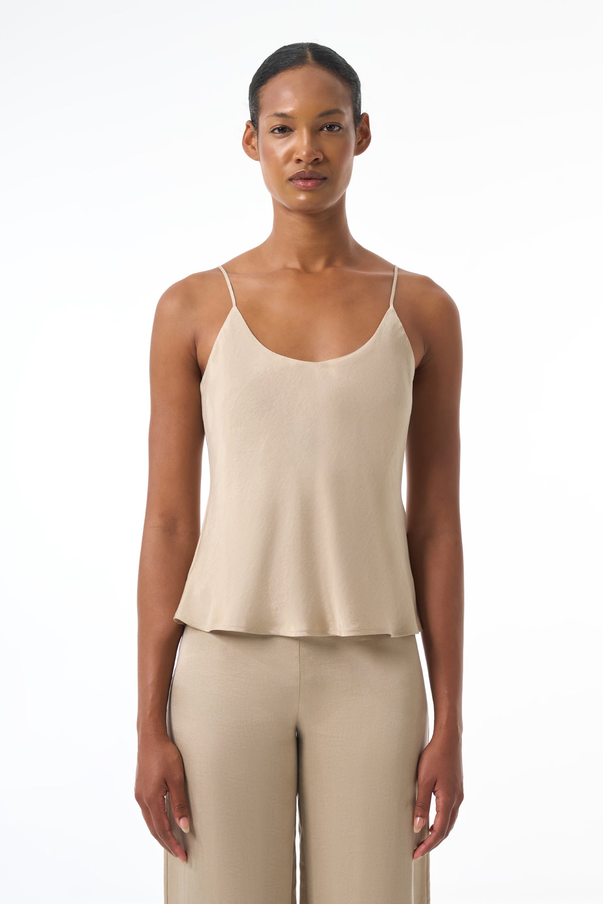 Woman wearing a beige tank top and pants on a white background