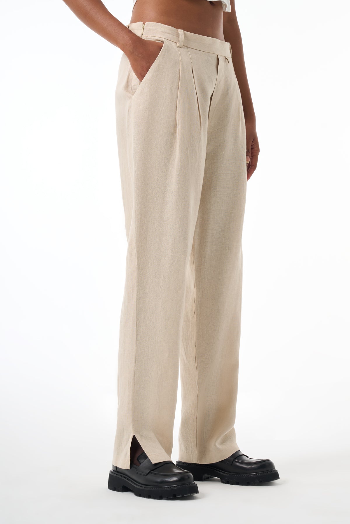 Beige pleated pants worn by a woman on a white background
